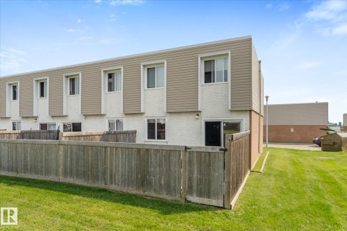 Rear exterior of a multi-unit property featuring wood fencing, a grass yard, and a paved area - 173 Cornell Court Nw, Edmonton, AB - Outdoor