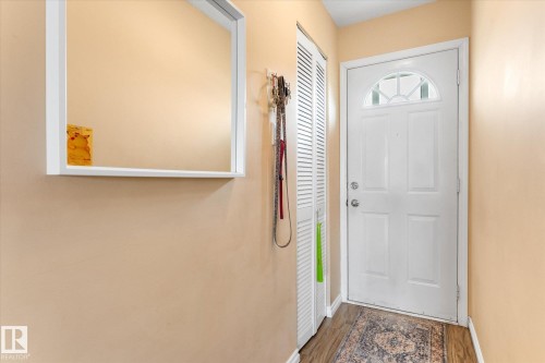 Entryway featuring a white paneled door with an arched transom window, wood-finish flooring, and a louvered bi-fold closet door - 173 Cornell Court Nw, Edmonton, AB - Indoor Photo Showing Other Room