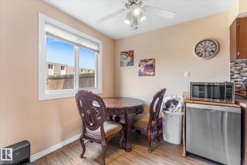 Bright kitchen dining area featuring a window with white trim, wood-finish flooring, a ceiling fan with integrated lighting, a built-in dishwasher, and a tiled backsplash - 173 Cornell Court Nw, Edmonton, AB - Indoor Photo Showing Dining Room