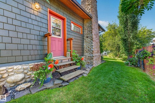 Cedar shake siding, river rock foundation, stone chimney, wood-plank steps, and a vibrant red entry door - 51 Itaska Beach, Rural Leduc County, AB 