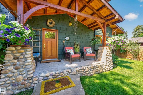 Front porch featuring a natural wood door, cedar shake siding, and stone accents - 51 Itaska Beach, Rural Leduc County, AB 