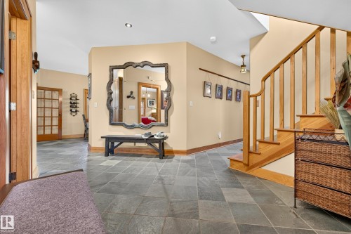 Entryway featuring slate tile flooring, a natural wood staircase with balusters, and a paneled wood-frame door - 51 Itaska Beach, Rural Leduc County, AB 