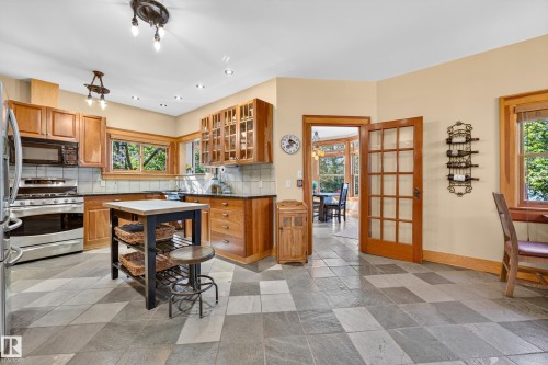 Kitchen featuring stone tile flooring, wood cabinetry with some glass-front doors, stainless steel appliances, and recessed lighting - 51 Itaska Beach, Rural Leduc County, AB 