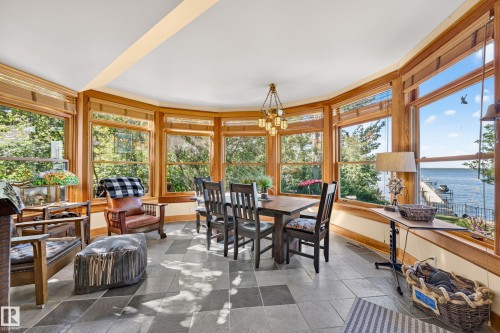 Bay window dining area featuring extensive natural light, wood window trim, slate-style flooring, and a multi-light chandelier - 51 Itaska Beach, Rural Leduc County, AB 