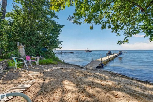 Sandy beachfront with a private dock extending into the water - 51 Itaska Beach, Rural Leduc County, AB 