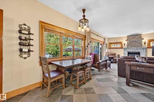 Stone tile flooring, stone fireplace with hearth, wood-framed windows, sliding glass door, and a built-in wine rack - 51 Itaska Beach, Rural Leduc County, AB 