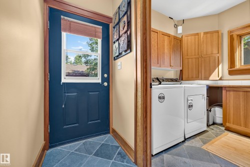 Slate tile flooring, natural wood cabinetry, a utility sink, and wood-finish trim - 51 Itaska Beach, Rural Leduc County, AB 