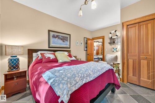 Neutral-toned walls, wood-finish bi-fold closet doors, and dark tile flooring - 51 Itaska Beach, Rural Leduc County, AB 