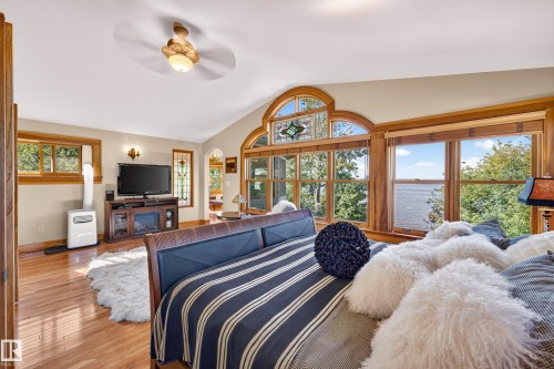 Hardwood flooring, vaulted ceiling with ceiling fan, large windows with wood trim, built-in entertainment console, and stained glass window feature - 51 Itaska Beach, Rural Leduc County, AB 