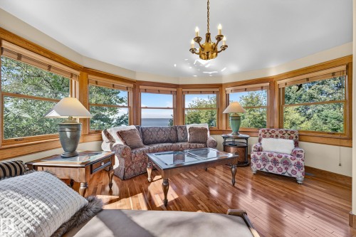 Bay window ensemble with wood-finish flooring, natural wood window trim, and a brass chandelier - 51 Itaska Beach, Rural Leduc County, AB 