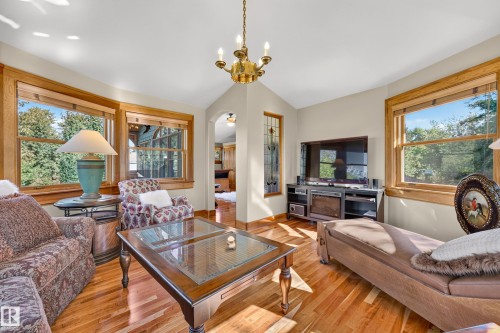 Hardwood flooring throughout, multiple windows with wood trim, vaulted ceiling, and an arched doorway - 51 Itaska Beach, Rural Leduc County, AB 