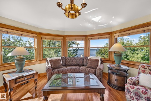 Bay window design with natural wood trim, hardwood flooring, and a decorative chandelier - 51 Itaska Beach, Rural Leduc County, AB 