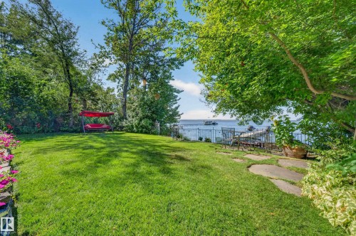 Manicured lawn with mature trees and a stone patio - 51 Itaska Beach, Rural Leduc County, AB 