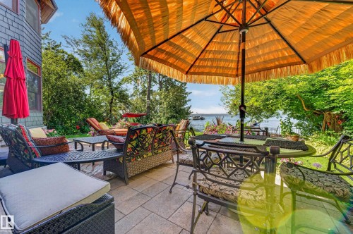 Paved patio with a water backdrop, surrounded by mature trees - 51 Itaska Beach, Rural Leduc County, AB 