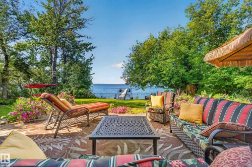 Expansive stone-finish patio with mature trees and direct water access featuring a dock - 51 Itaska Beach, Rural Leduc County, AB 