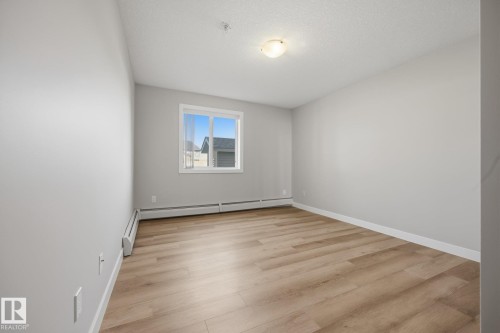 Neutral gray walls, wood-finish flooring, white window trim, and a ceiling-mounted light fixture - #122 240 Spruce Ridge Rd, Spruce Grove, AB 