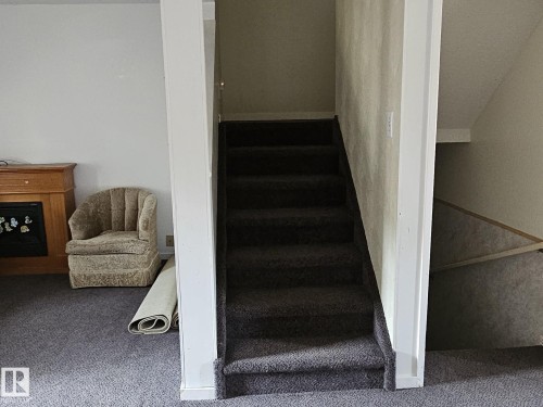 Carpeted staircase with white trim, wood-finish mantel with firebox, and carpeted flooring - 14674 54 Street Northwest, Edmonton, AB 