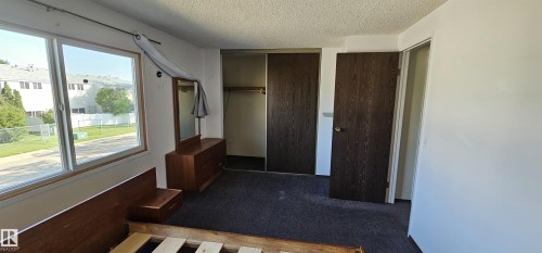 Wall-to-wall carpeting with a large window and wood-finish trim - 14674 54 Street Northwest, Edmonton, AB 
