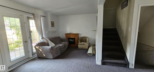 Carpeted flooring, white wall finishes, built-in shelving, wood-finish mantel with an electric fireplace, and a carpeted staircase - 14674 54 Street Northwest, Edmonton, AB 