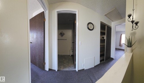 Carpeted hallway featuring multiple doorways, a built-in closet with shelving, and an overhead access panel - 14674 54 Street Northwest, Edmonton, AB 