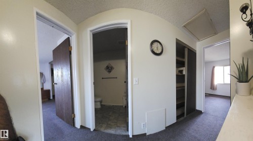 Hallway with carpet flooring, built-in shelving, and multiple doorways - 14674 54 Street Northwest, Edmonton, AB 