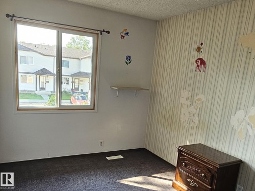 Dual-pane window with wood-finish trim, textured wall covering, and dark carpeting - 14674 54 Street Northwest, Edmonton, AB 