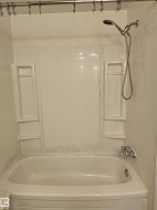 Bathtub with integrated shelving and a handheld shower fixture - 