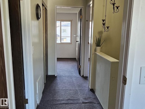 Interior hallway with dark carpet flooring, light-toned walls, and wood-finish doors - 14674 54 Street Northwest, Edmonton, AB 