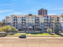 Multi-story building featuring blue and cream-colored siding, multiple glass-paneled balconies, and a paved street - 
