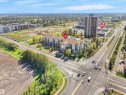 Multi-story residential buildings with balconies, adjacent to a wide paved road, and surrounded by mature trees - #206 12111 51 Av Nw, Edmonton, AB 