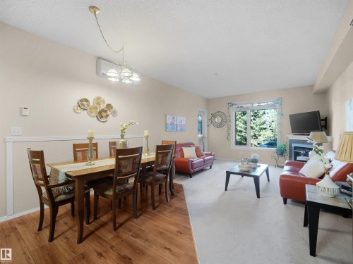 Open-concept living area with wood-finish flooring, recessed lighting, and a prominent window - #206 12111 51 Av Nw, Edmonton, AB 
