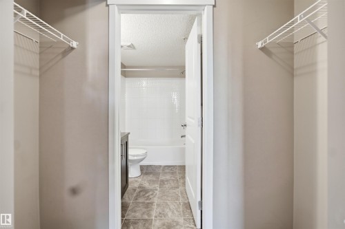 Bathroom featuring a white bathtub with tile surround, a toilet, and a dark wood-finish vanity - #225 1510 Watt Dr Sw, Edmonton, AB 
