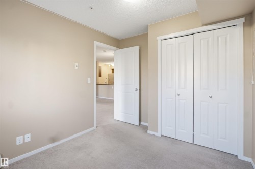 Neutral-toned walls, light-colored carpet flooring, and a white bi-fold closet - #225 1510 Watt Dr Sw, Edmonton, AB 