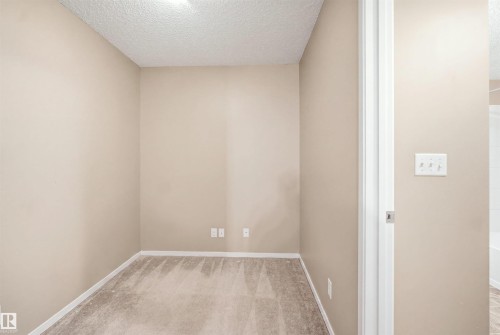 Neutral-toned walls, textured ceiling, and carpeting - #225 1510 Watt Dr Sw, Edmonton, AB 