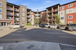 Multi-story building featuring balconies, a paved parking area, and an entrance with prominent building numbering - 