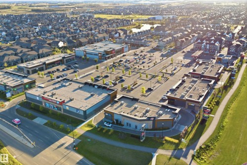 Mixed-use development featuring commercial retail spaces, surface parking, and multi-unit residential buildings - #225 1510 Watt Dr Sw, Edmonton, AB 