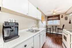 Kitchen featuring white cabinetry, a stainless steel sink, wood-finish flooring, and a ceiling fan - 