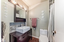Modern vanity with a rectangular vessel sink, mosaic tile backsplash, and wood-finish flooring - 