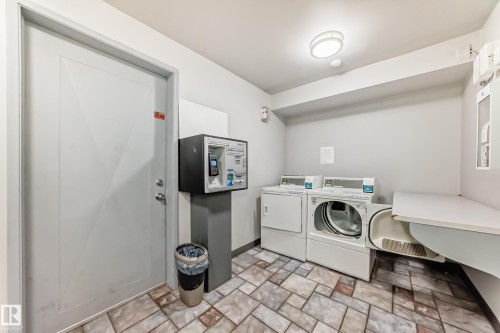 Laundry area featuring tile flooring, two white laundry machines, a built-in counter, and recessed lighting - #302 10606 123 St Nw, Edmonton, AB 