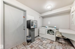 Laundry area featuring tile flooring, two white laundry machines, a built-in counter, and recessed lighting - 