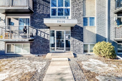 Building entrance with stone facade detailing, glass double doors, and a concrete pathway - #302 10606 123 St Nw, Edmonton, AB 