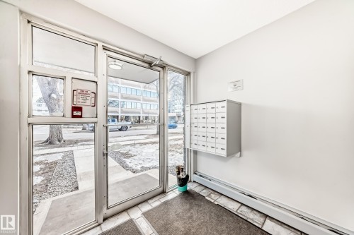 Building entry with clear glass doors, white walls, and wall-mounted mailboxes - #302 10606 123 St Nw, Edmonton, AB 