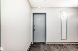 Wall-mounted sconce with circular light fixture, gray painted door with metal hardware, and patterned floor covering - 