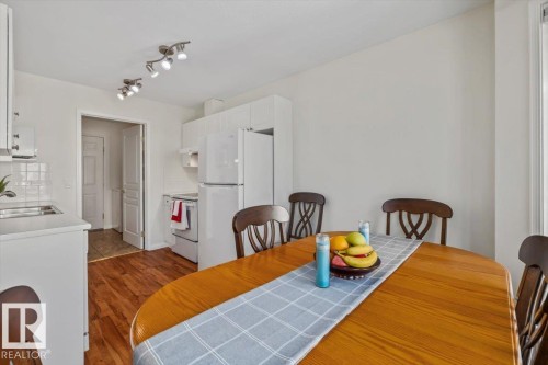 Compact kitchen with white cabinetry, white appliances, track lighting, and wood-finish flooring - #92 13320 124 St Nw, Edmonton, AB 