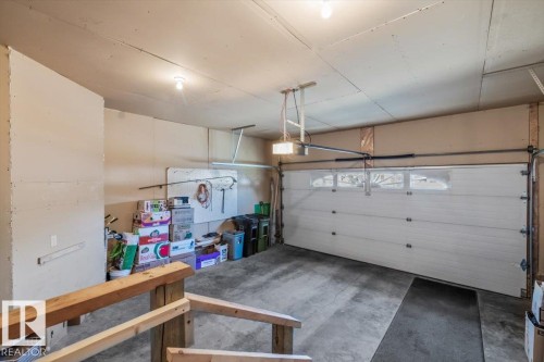 Attached garage with a sectional garage door, upper window panels, and a concrete floor - #92 13320 124 St Nw, Edmonton, AB 