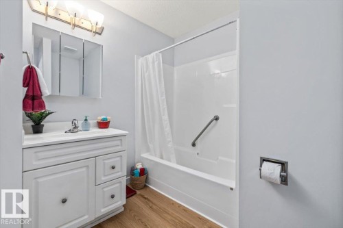 White vanity with paneling and storage, chrome faucet, and three-door mirrored medicine cabinet - #92 13320 124 St Nw, Edmonton, AB 