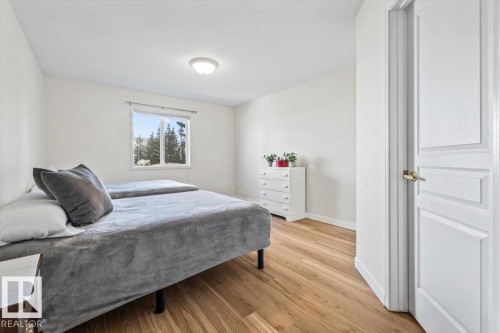 Wood-finish flooring with a white trim, a large window, white walls, and a ceiling-mounted light fixture - #92 13320 124 St Nw, Edmonton, AB 