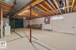 Unfinished basement space featuring exposed wooden joists, utility piping, and a concrete floor - 