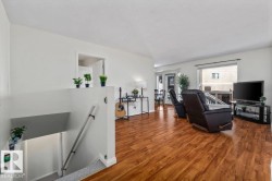 Wood-finish flooring, white wall finishes, and a large window providing natural light - 