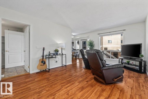 Wood-finish flooring throughout, white walls, and a large window with white trim - #92 13320 124 St Nw, Edmonton, AB 